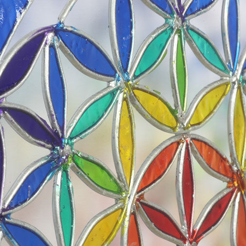 Round Flower of Life suncatcher with an overlapping-circle pattern in full rainbow resin, bordered by a deep blue ring