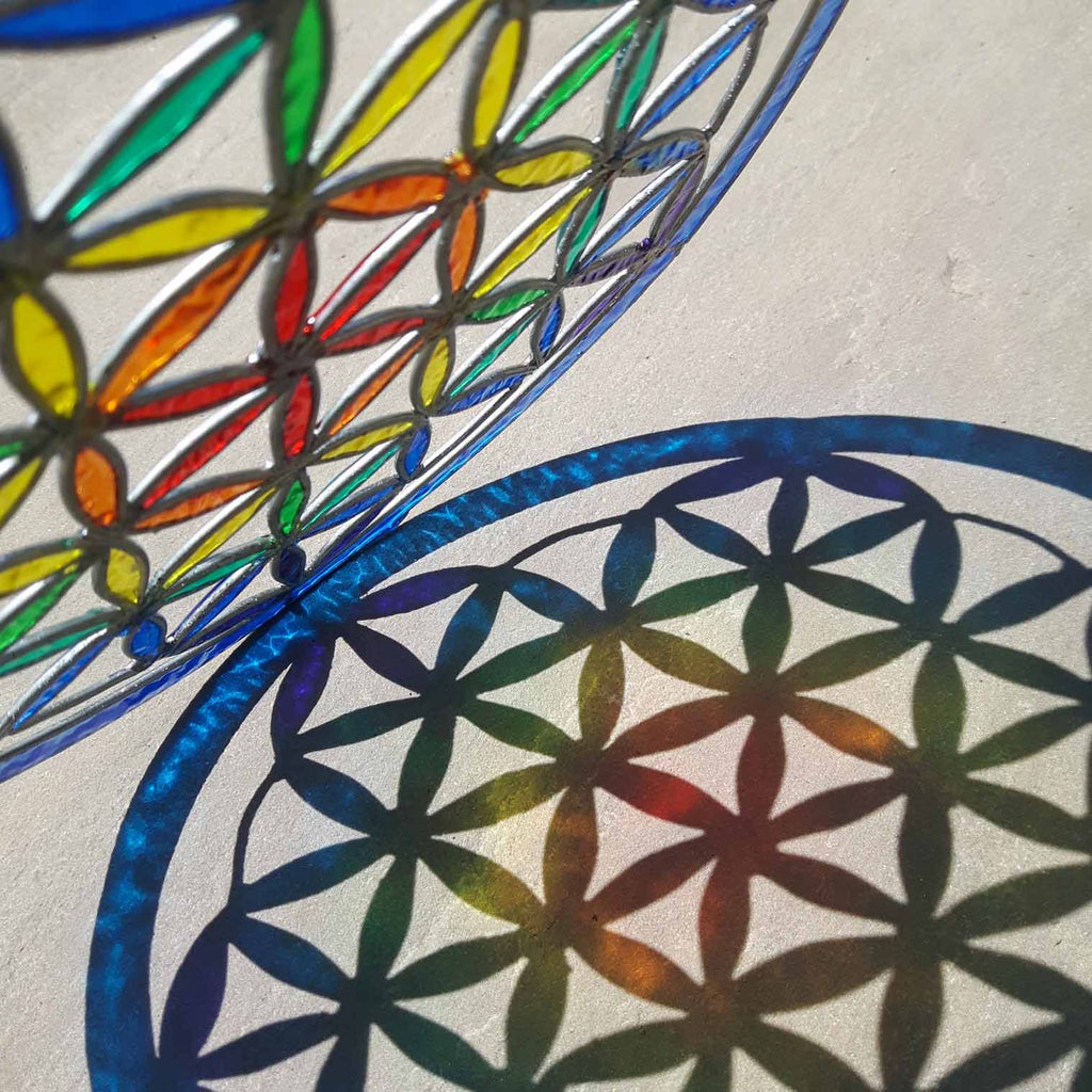 Round Flower of Life suncatcher with an overlapping-circle pattern in full rainbow resin, bordered by a deep blue ring