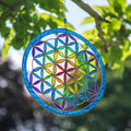 Round Flower of Life suncatcher with an overlapping-circle pattern in full rainbow resin, bordered by a deep blue ring
