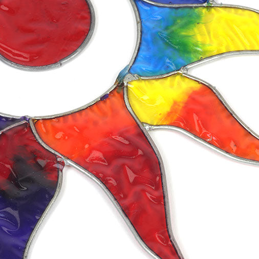 Sun-shaped suncatcher with twelve tapered rays in red, blue, yellow, green, orange and purple resin around a white centre, in a soldered metal frame