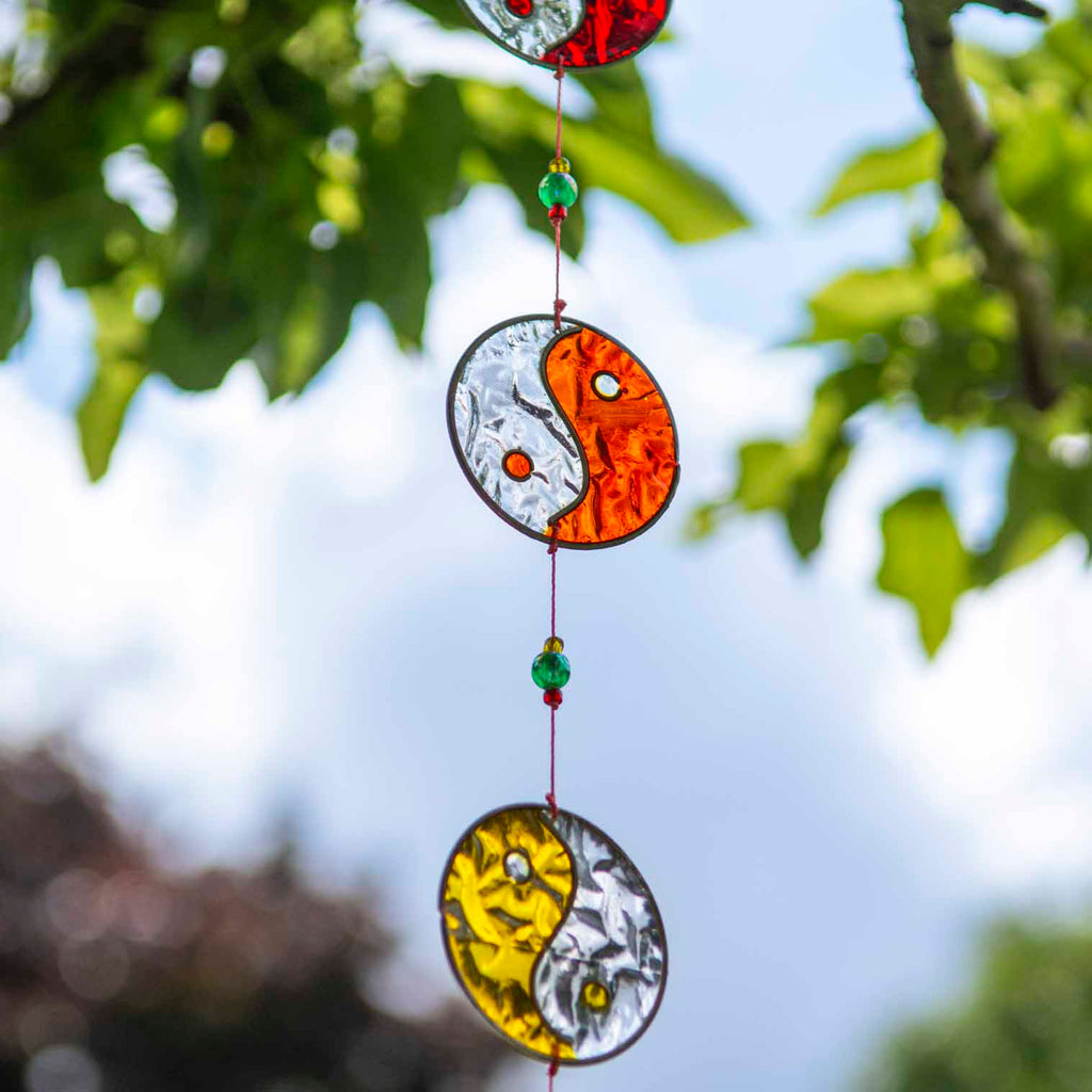 Vertical string of five yin yang suncatchers in contrasting colour pairings, with coloured beads strung between the discs