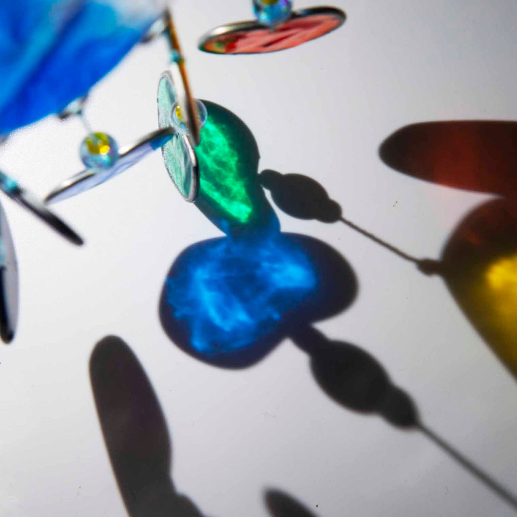 Blue resin cloud suncatcher with six threads of rainbow hearts dangling beneath in jewel tones of red, orange, yellow, green, blue and purple