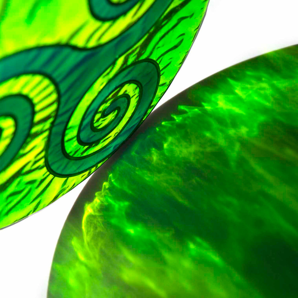 Round deep-green suncatcher with a Celtic triskele of three interlocking spirals, in a soldered metal frame