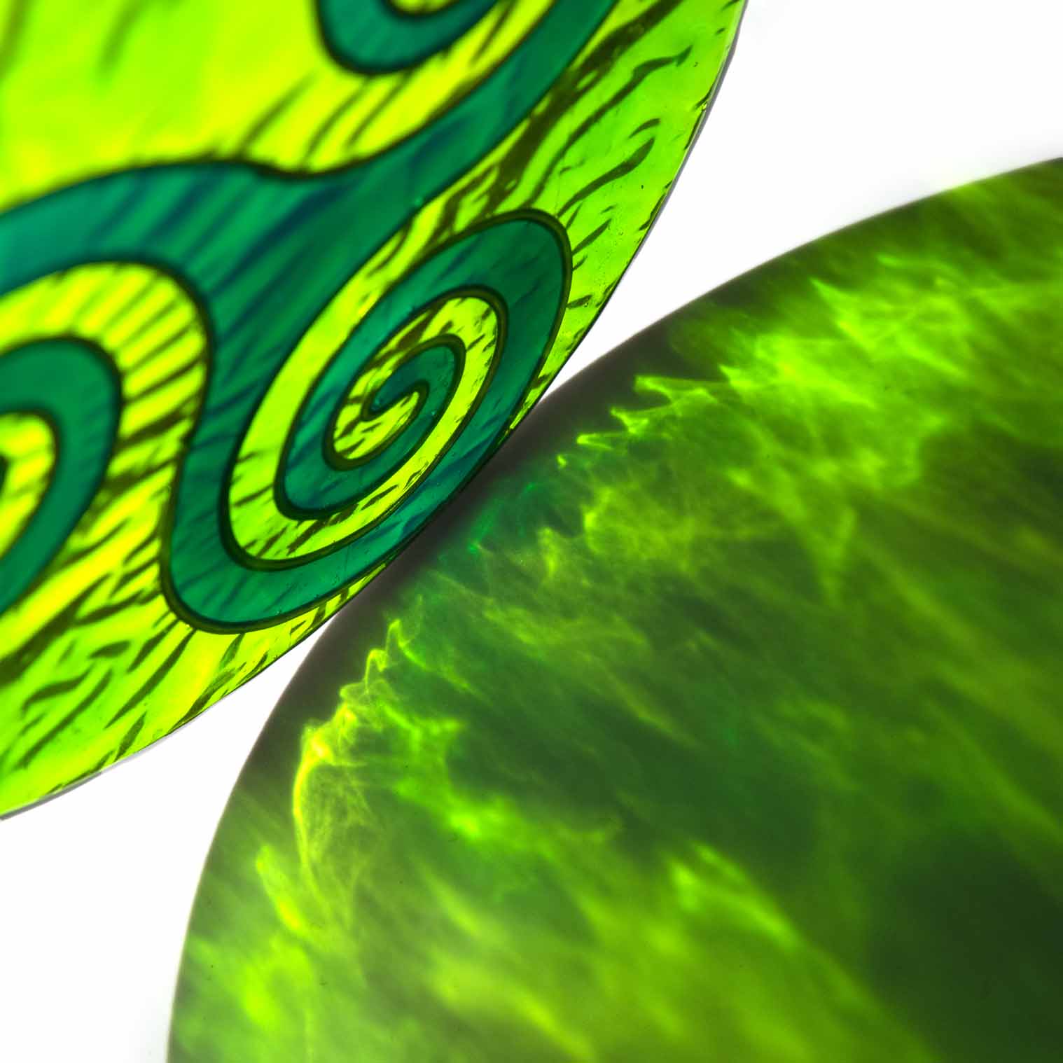 Round deep-green suncatcher with a Celtic triskele of three interlocking spirals, in a soldered metal frame