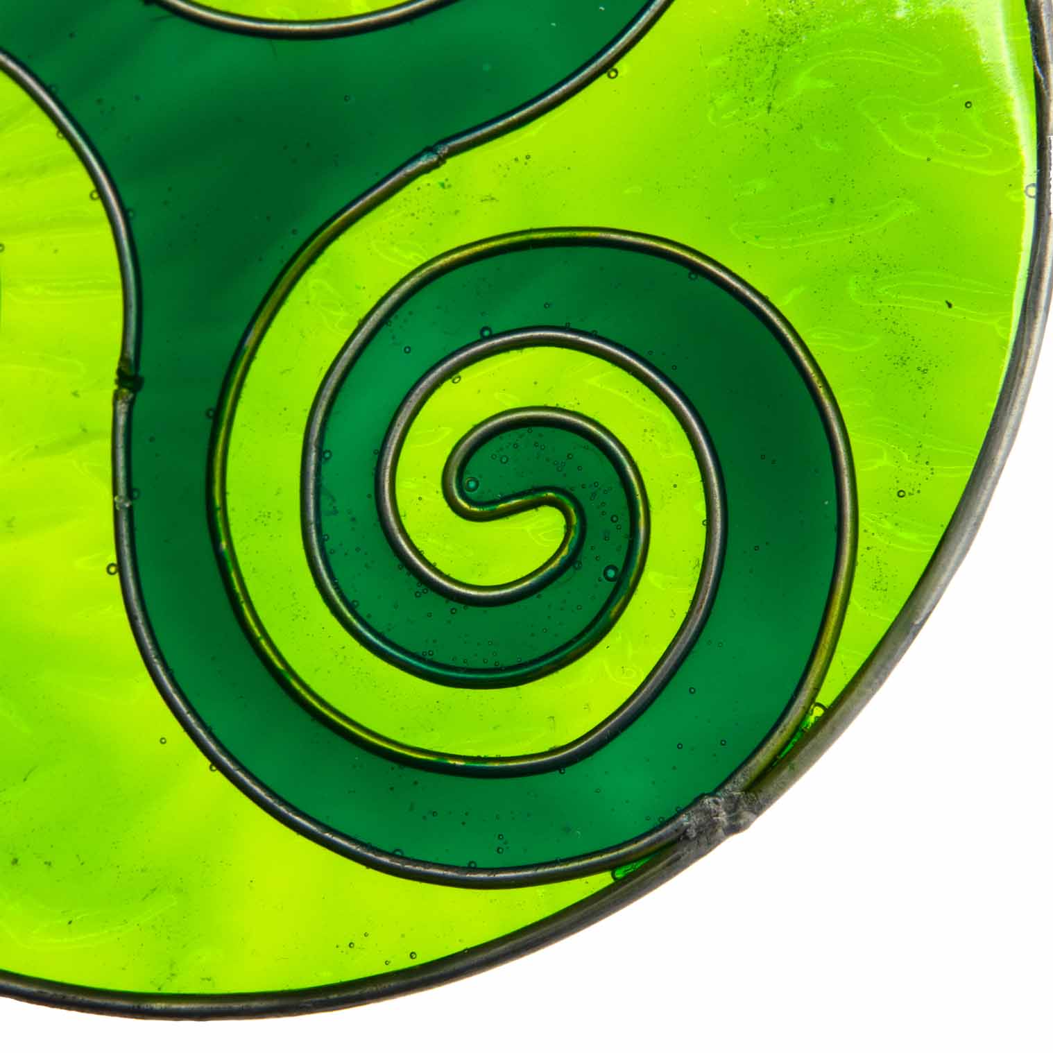 Round deep-green suncatcher with a Celtic triskele of three interlocking spirals, in a soldered metal frame