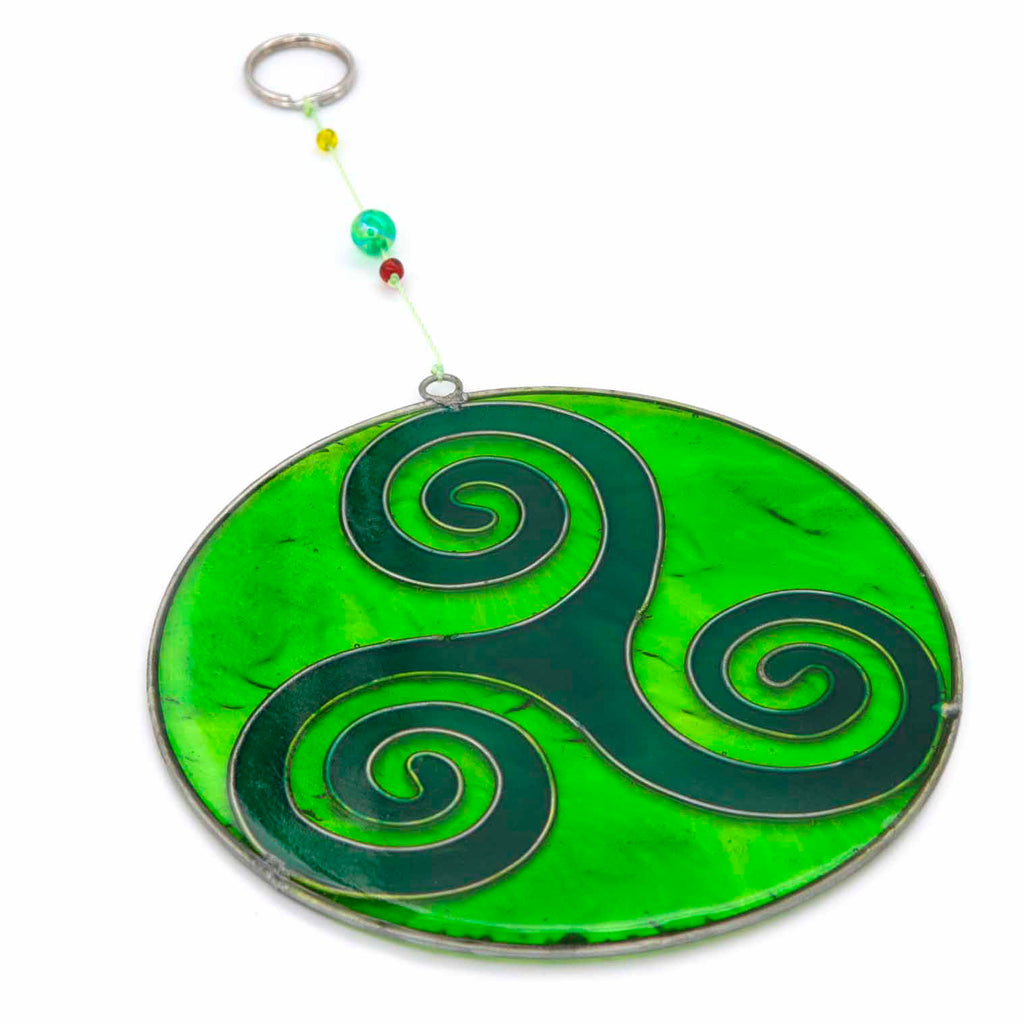 Round deep-green suncatcher with a Celtic triskele of three interlocking spirals, in a soldered metal frame