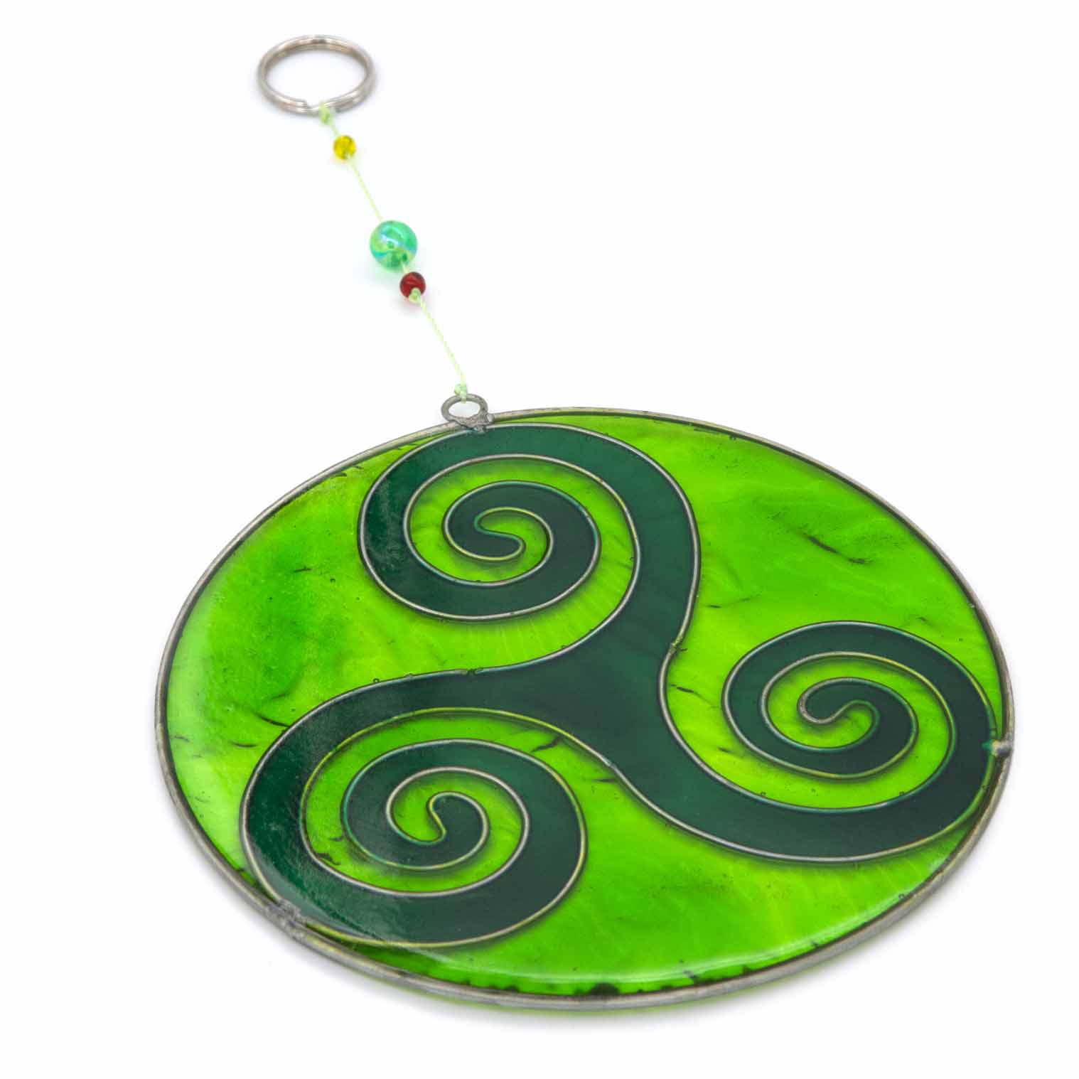 Round deep-green suncatcher with a Celtic triskele of three interlocking spirals, in a soldered metal frame