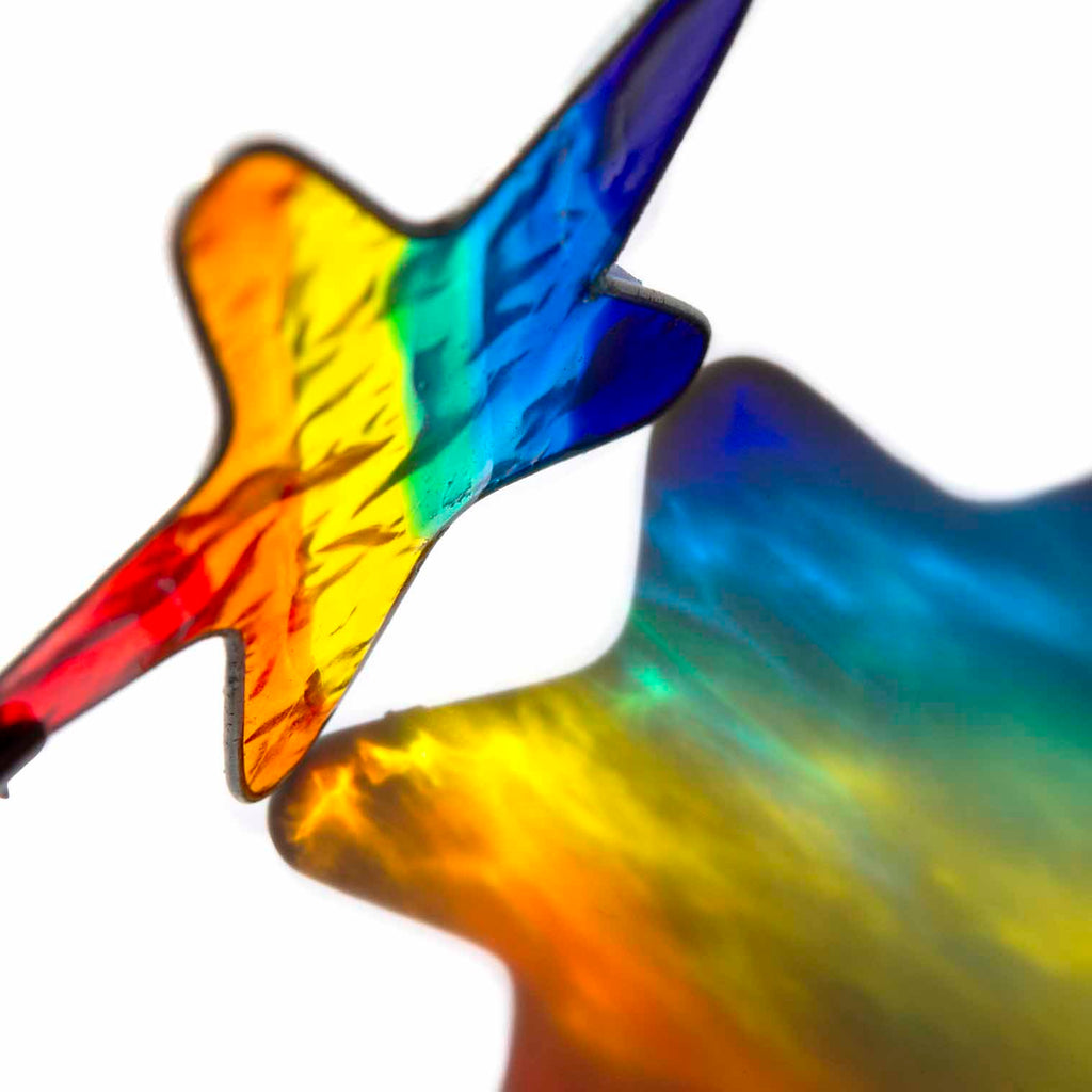 Small star-shaped suncatcher with a bright rainbow stripe running across it, in a soldered metal frame