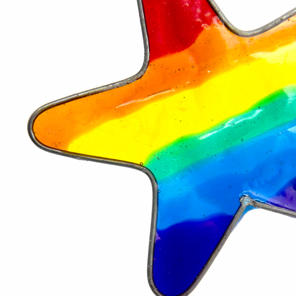 Small star-shaped suncatcher with a bright rainbow stripe running across it, in a soldered metal frame