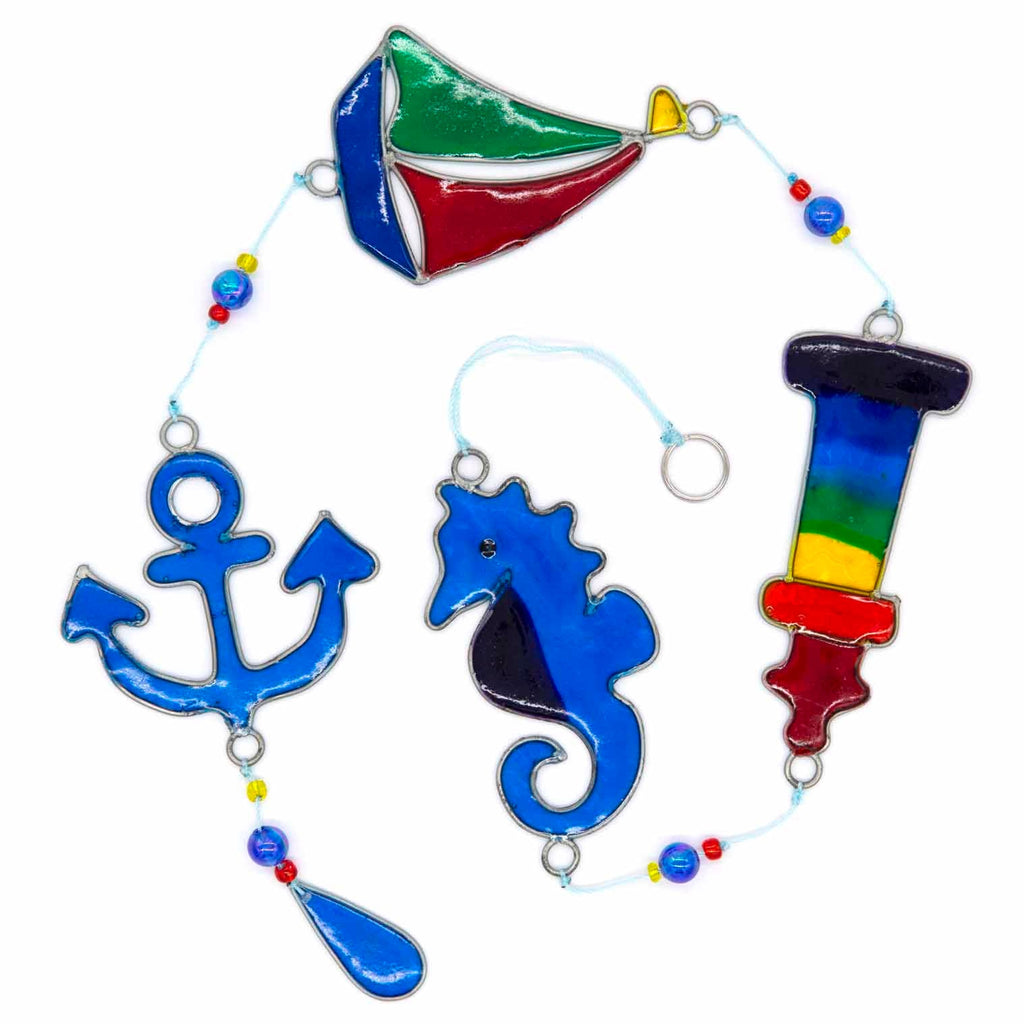 Nautical hanging suncatcher with a blue seahorse, a deep blue anchor and a red striped lighthouse strung vertically in soldered metal frames