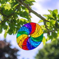Round suncatcher with bold rainbow segments curving from the centre in a spinning pinwheel pattern, in a soldered metal frame