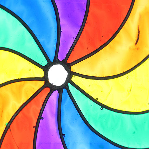 Round suncatcher with bold rainbow segments curving from the centre in a spinning pinwheel pattern, in a soldered metal frame