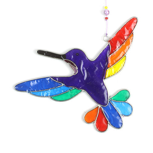 Hummingbird suncatcher in mid-flight with a blue and turquoise body and a fan of rainbow tail feathers, in a hand-shaped soldered metal frame