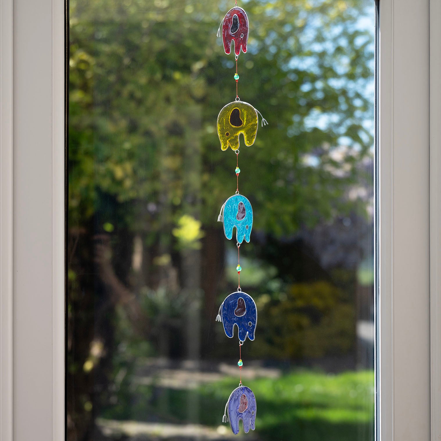 Vertical string of five jewel-tone elephant suncatchers in red, yellow, green, blue and purple, in soldered metal frames