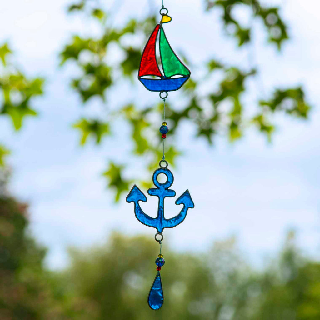 Nautical hanging suncatcher with a blue seahorse, a deep blue anchor and a red striped lighthouse strung vertically in soldered metal frames