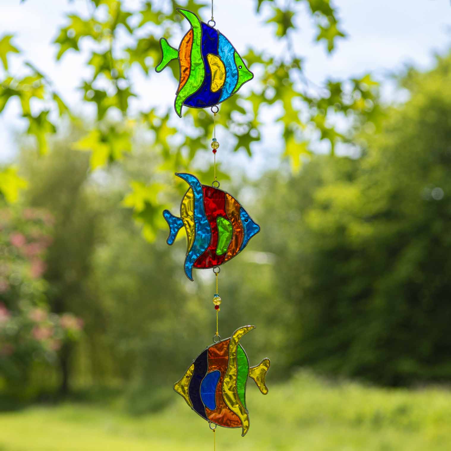 Vertical string of three angel fish suncatchers in bright turquoise, cobalt, lime and ruby, in soldered metal frames