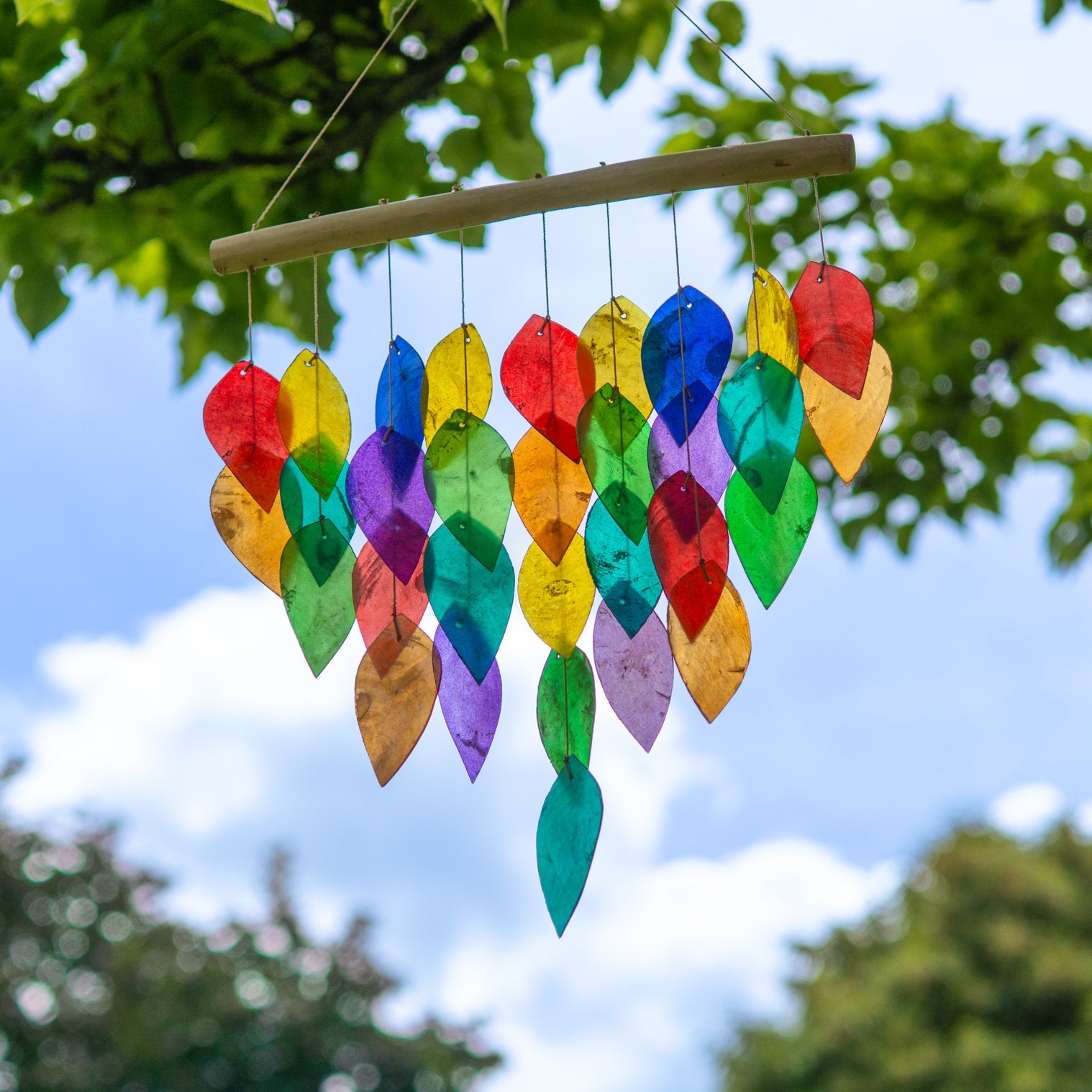 Hanging windchime of rainbow-coloured shell leaves strung from a length of bamboo