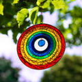 Round suncatcher with concentric rings of rainbow colour radiating from a deep blue centre, in a soldered metal frame