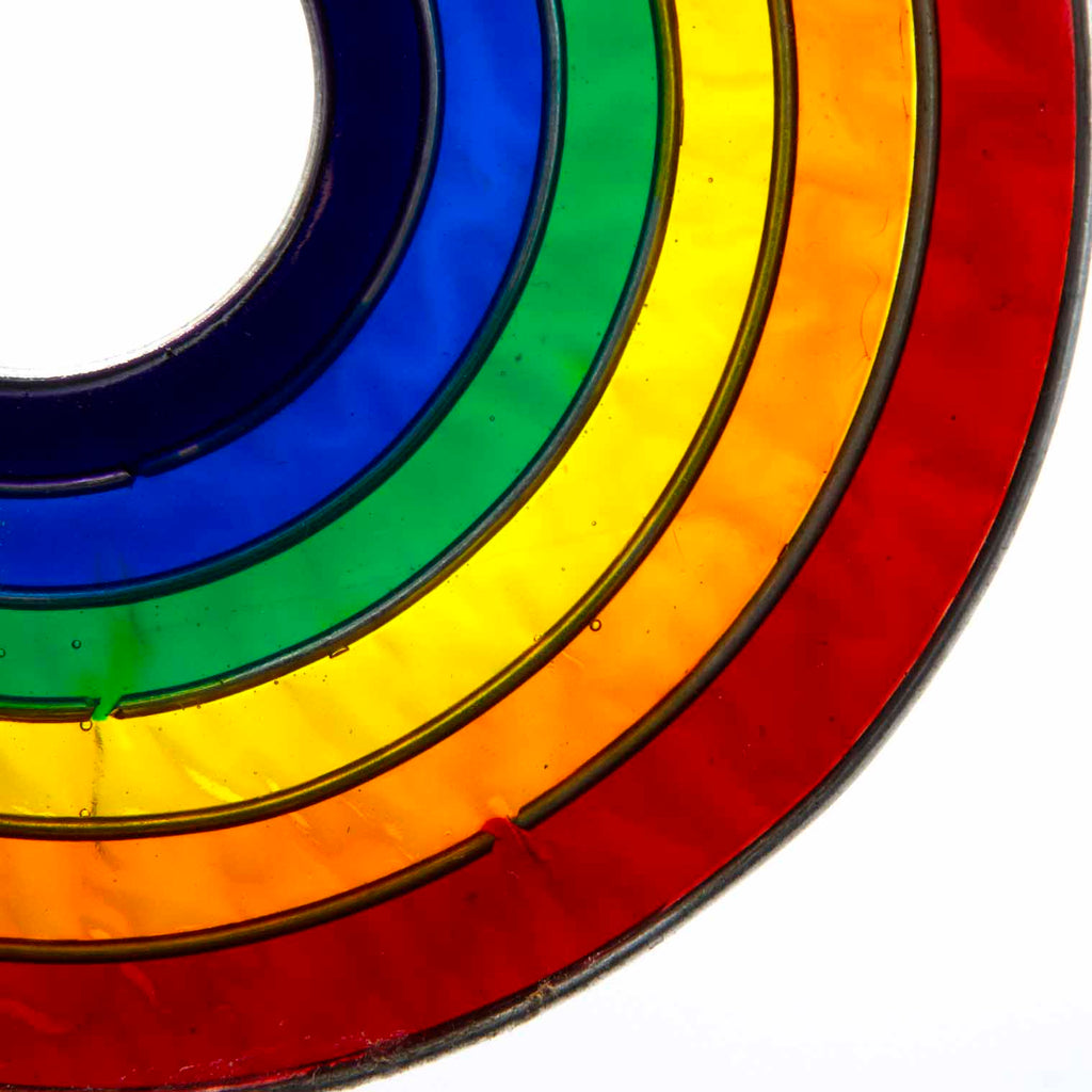 Round suncatcher with concentric rings of rainbow colour radiating from a deep blue centre, in a soldered metal frame