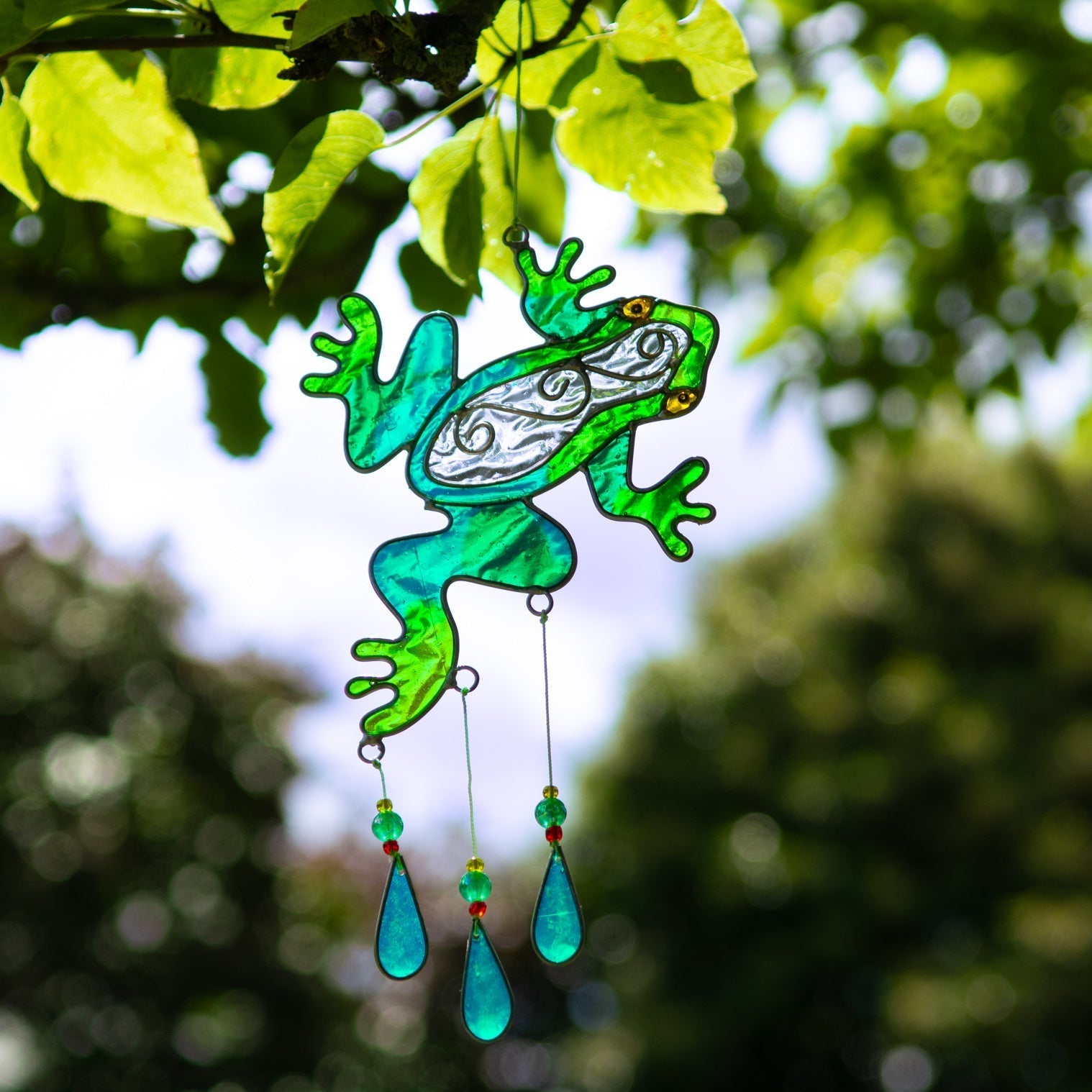 Cheerful green frog suncatcher in translucent panels with a painted face and dangling teardrop beads beneath
