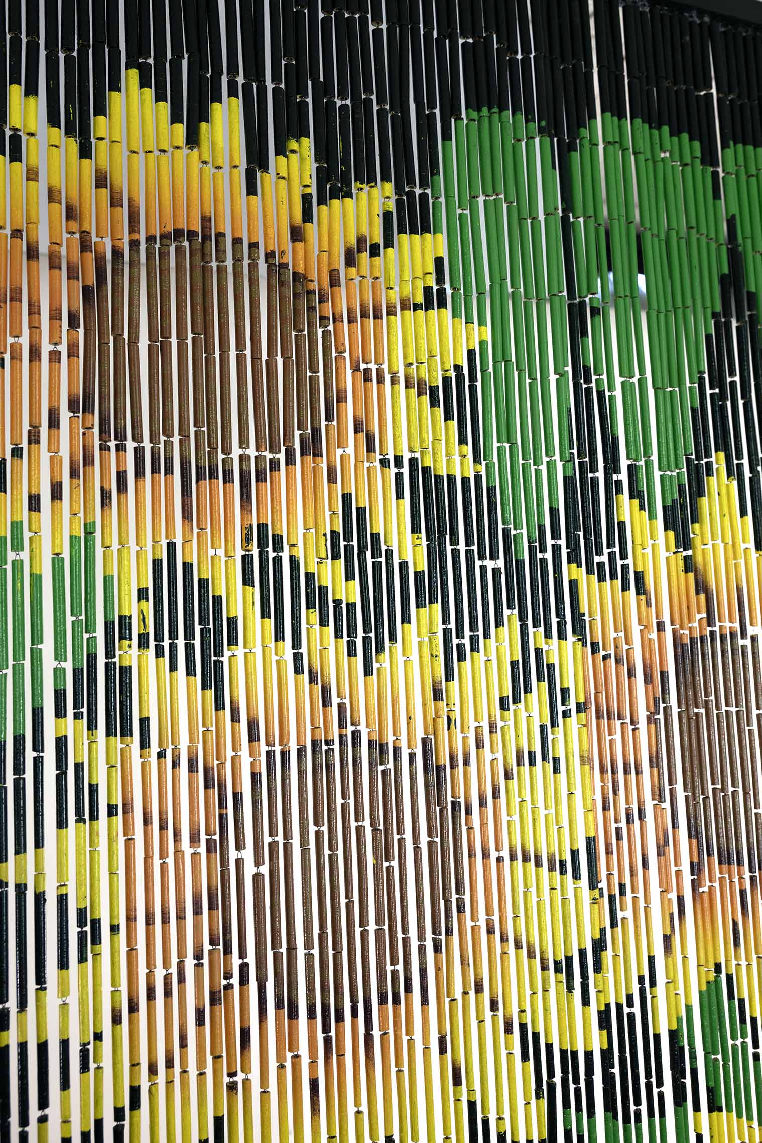 Hand-painted bamboo bead curtain with a bright yellow sunflower design, hanging in a doorway
